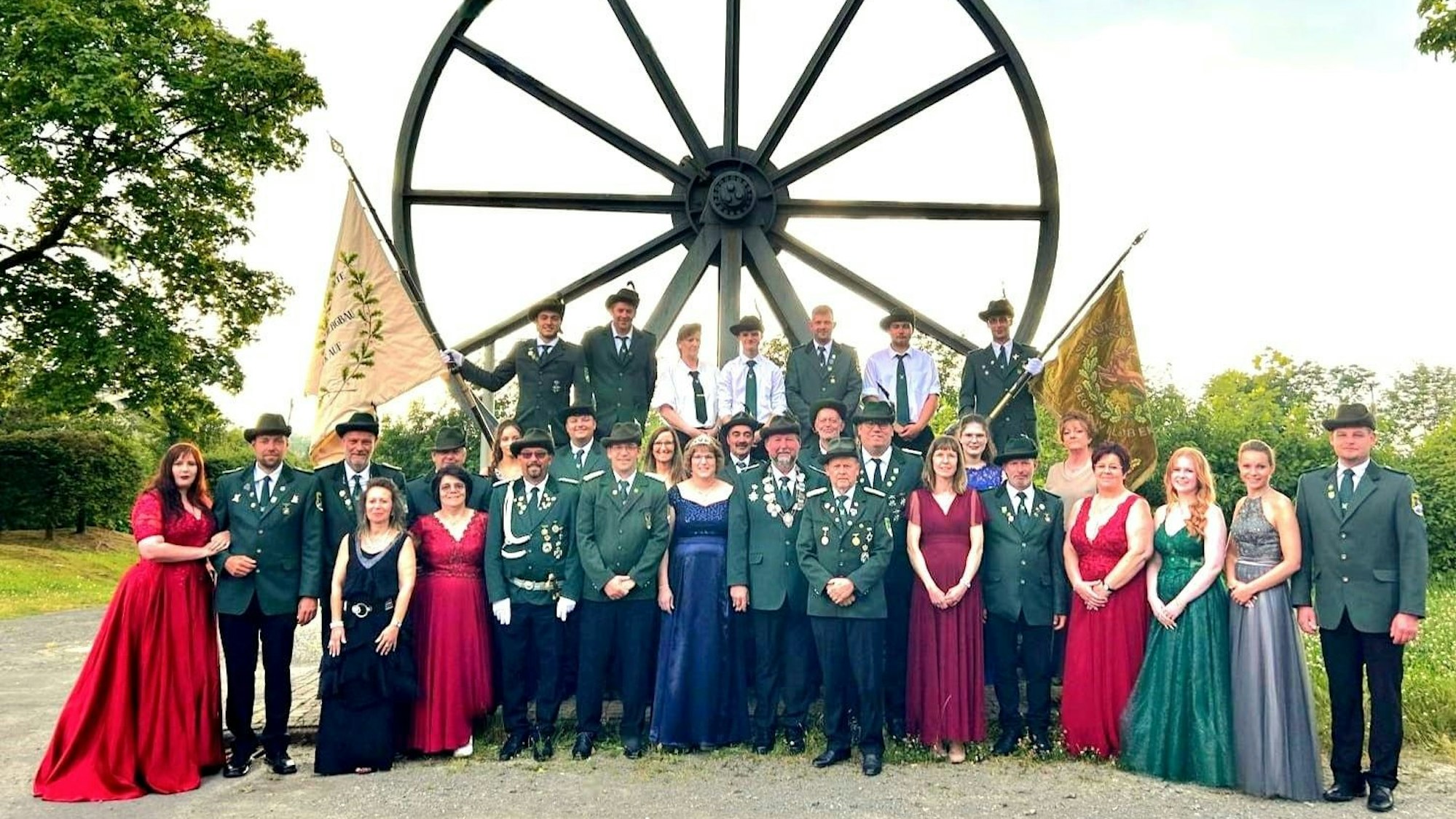 Festlich gekleidete Schützen vor einem Grubenrad.