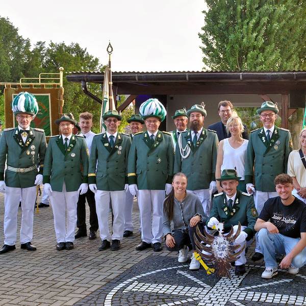 Eine Gruppe Männer steht in grün-weißer Schützen-Uniform und mit ein paar Frauen in ziviler Kleidung auf einem Platz.