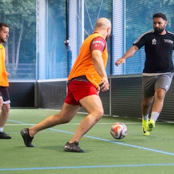 Spieler des Euskirchener TSC trainieren in einer Sporthalle das Fußballspielen. Einige tragen orangefarbene Leibchen.