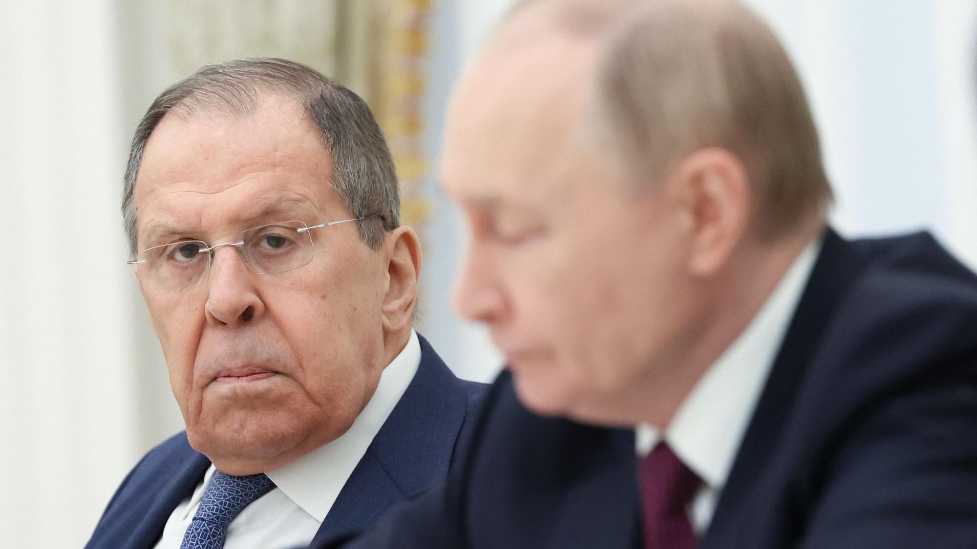 Russlands Außenminister Sergej Lawrow schaut in die Kamera. Im Vordergrund ist Kremlchef Wladimir Putin unscharf zu sehen. (Archivbild)