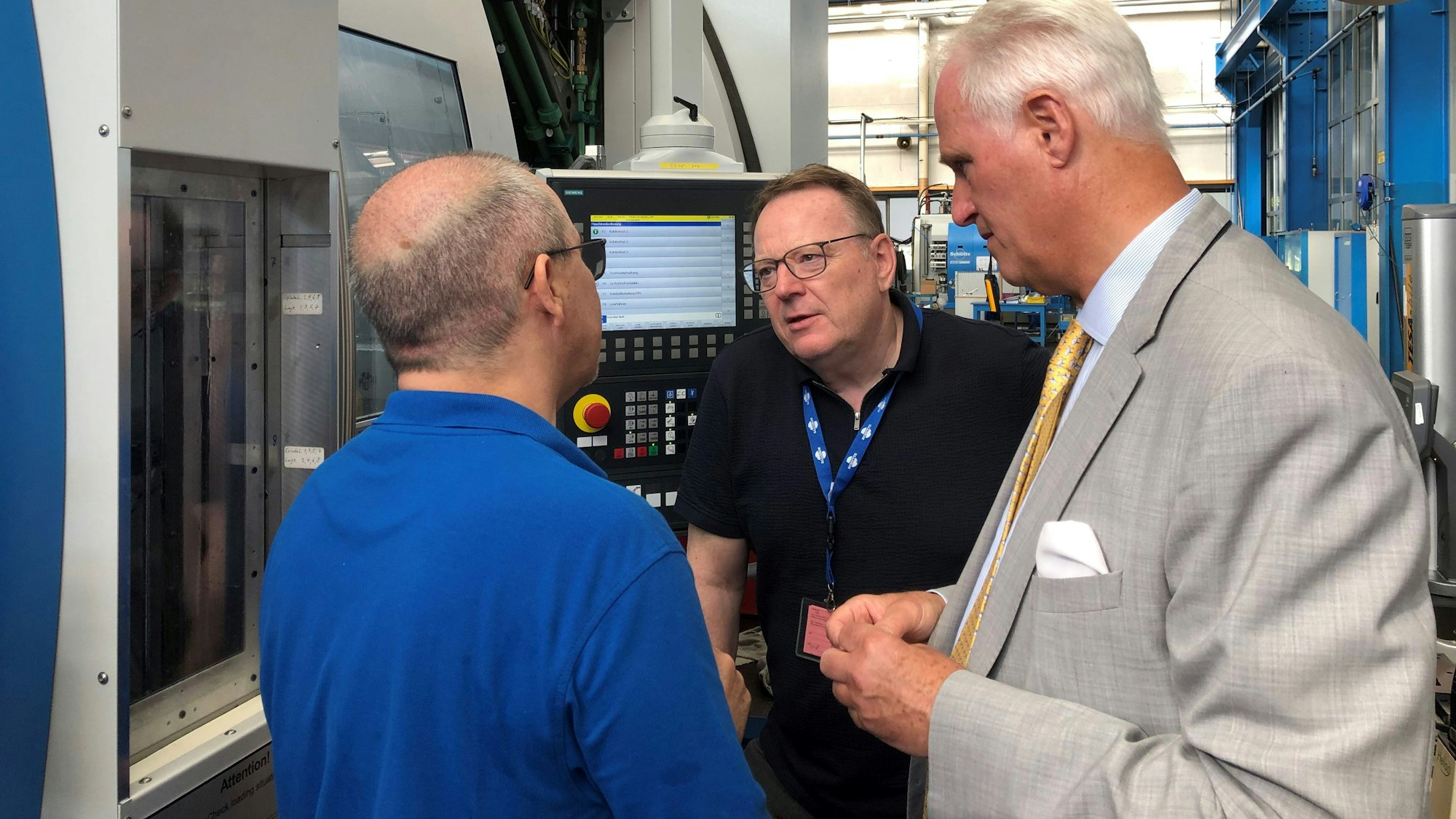 SPD-OB-Kandidat Torsten Burmester (M.) im Gespräch mit Schütte-Geschäftsführer Martin Welcker (r.) und Servicetechniker Hakan Hariklar vor einer Schütte-Werkzeugmaschine.
