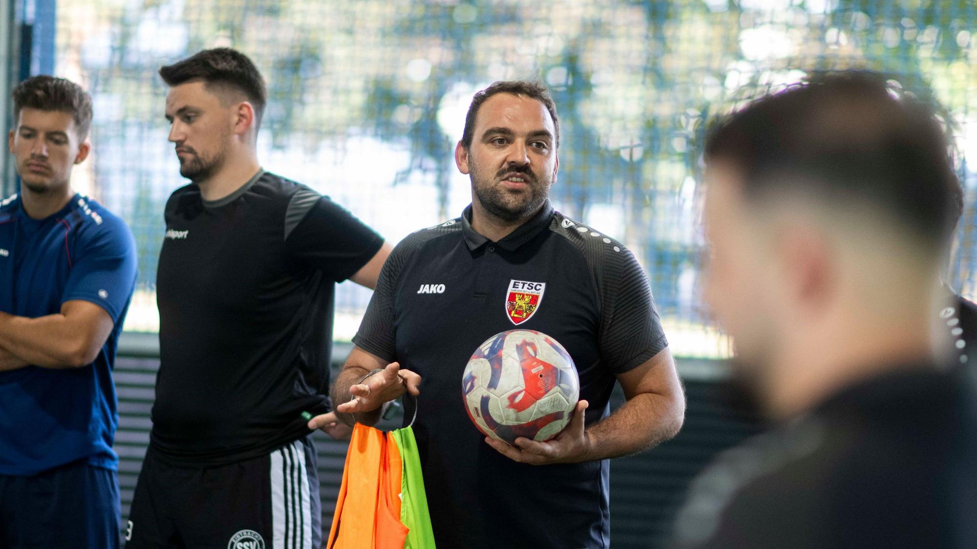 Salih Yavuz hält einen Ball in einer Hand und redet mit seinen Spielern.