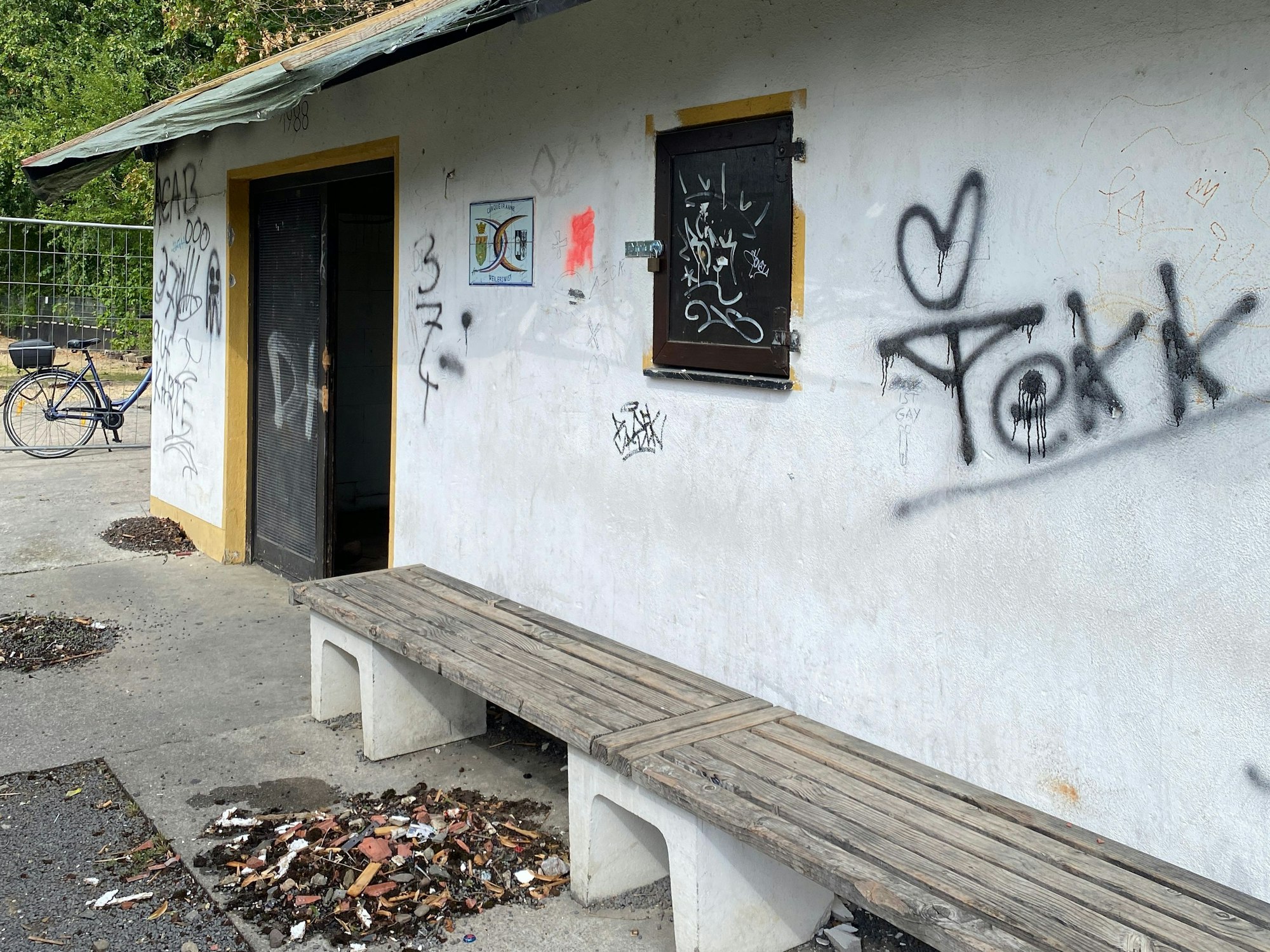 Auf der Fassade des Vereinshauses sind unschöne Schmierereien. Auf dem Boden davor liegen Müll und Dreck.