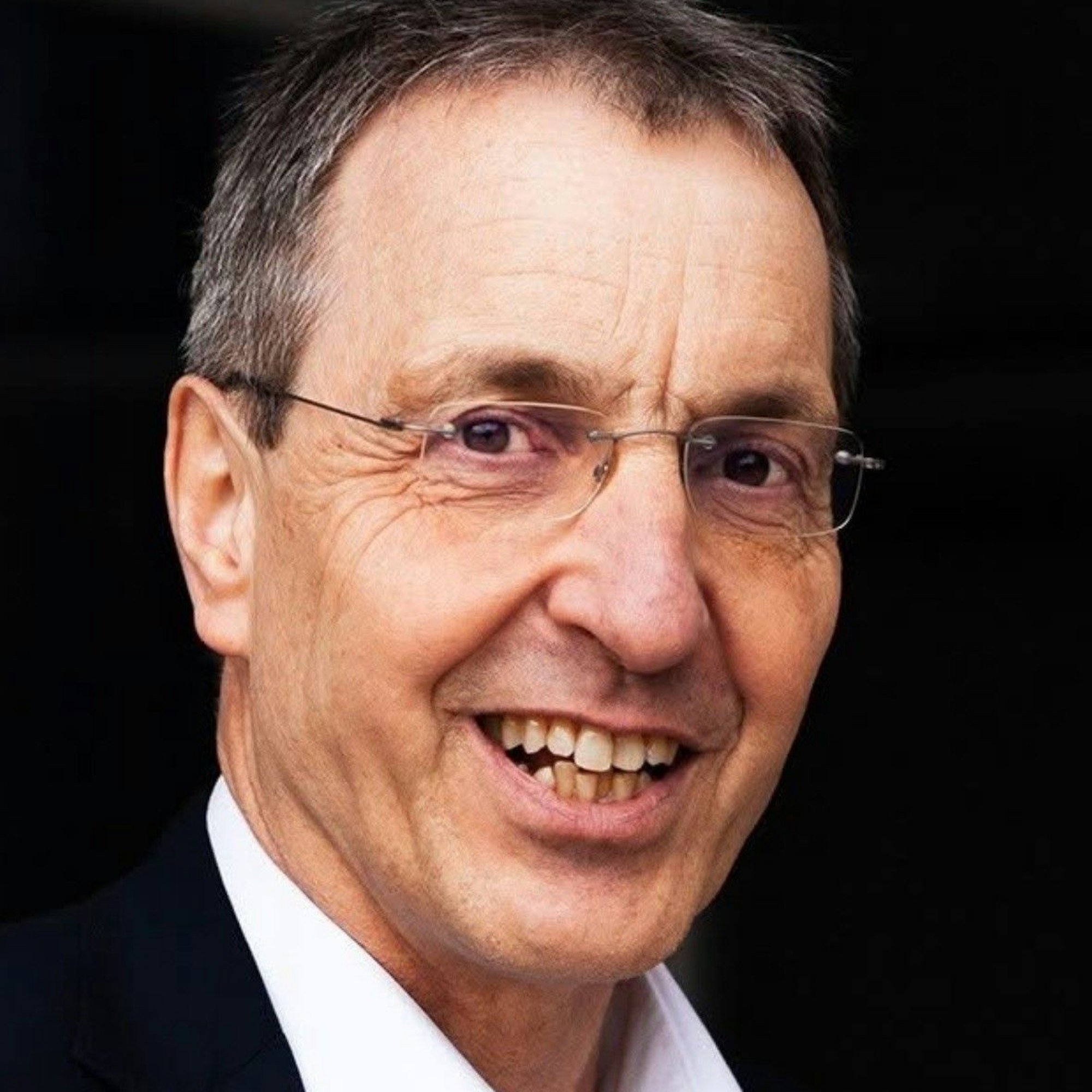 Auf dem Bild ist das Portrait von Raimund Hegwald zu sehen, er lacht in die Kamera.