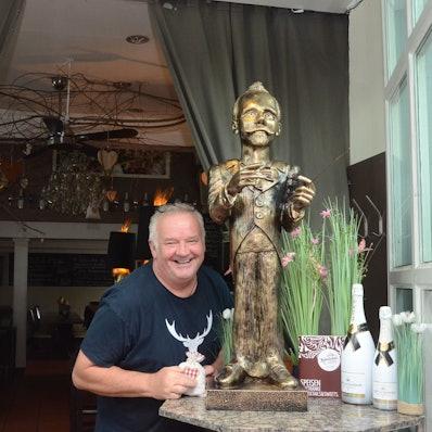 Ein Mann im T-Shirt steht neben einer Skulptur des Komponisten Engelbert Humperdinck.