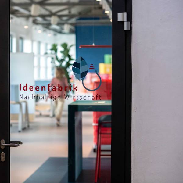 Auf einer Glastür ist die Aufschrift „Ideenfabrik Nachhaltige Wirtschaft“ aufgeklebt