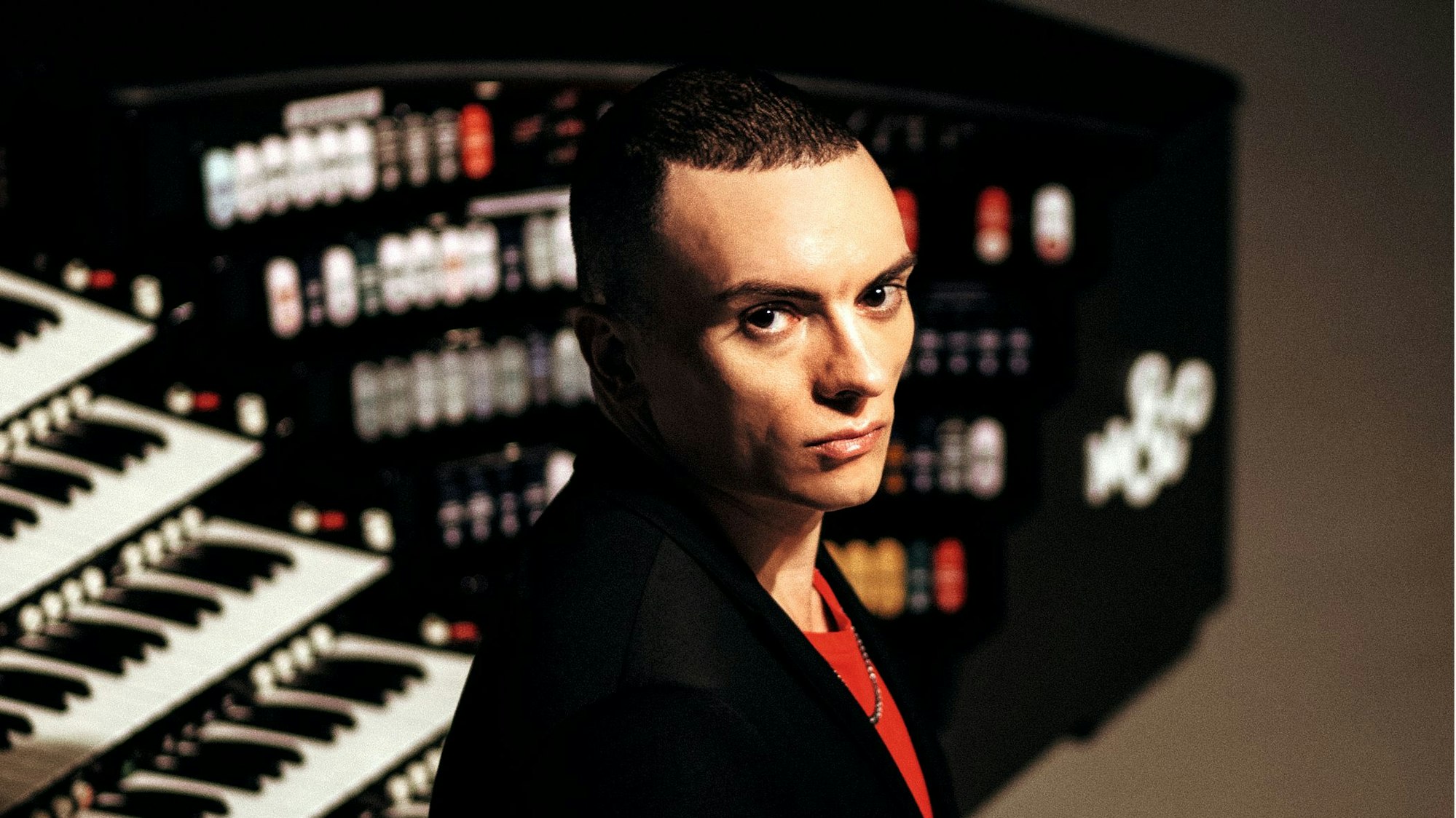 Ein Mann mit sehr kurzen Haaren schaut sehr ernst in die Kamera.