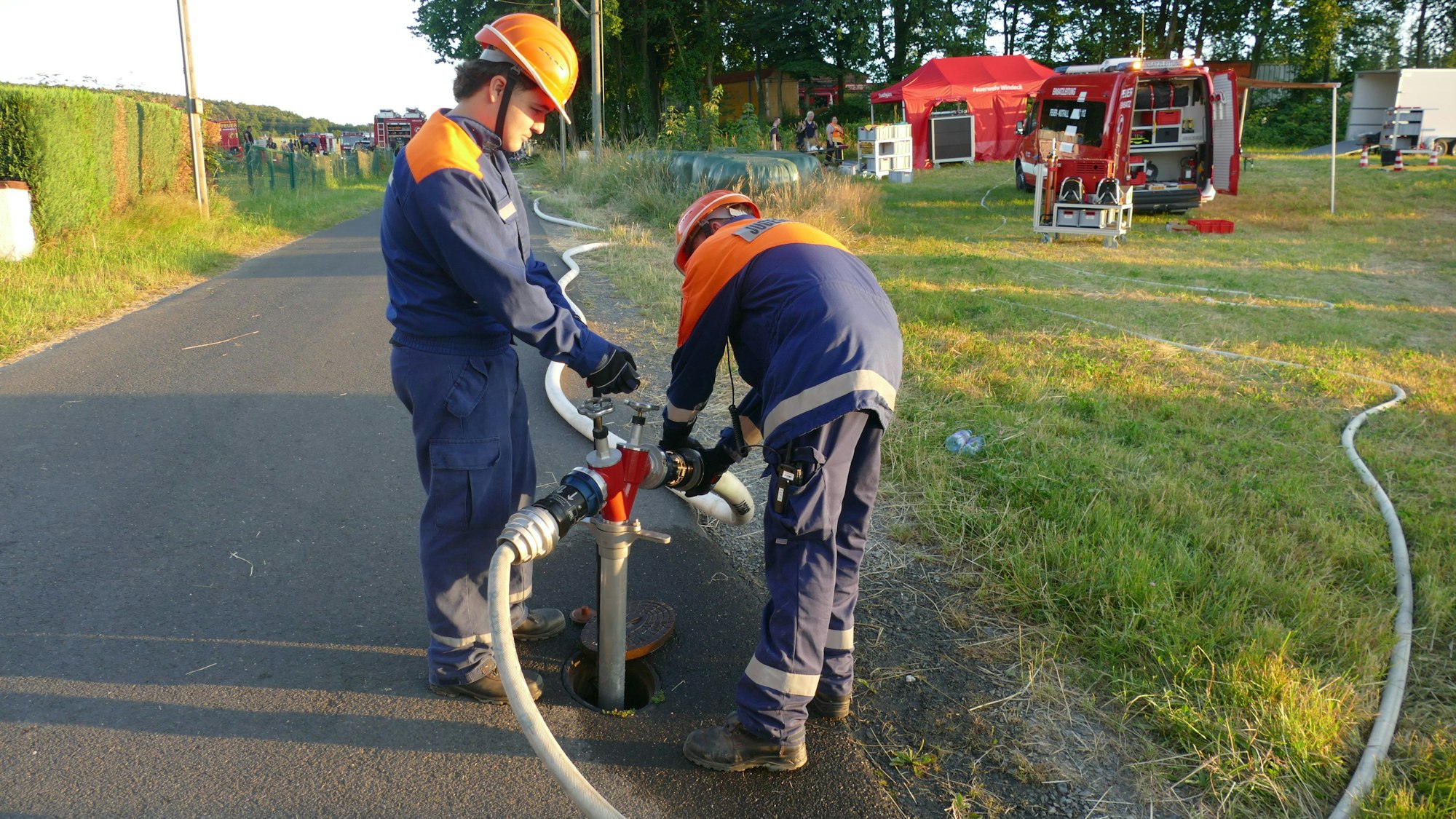 Zwei Jugendliche schließen ein Standrohr an einen Hydranten an.