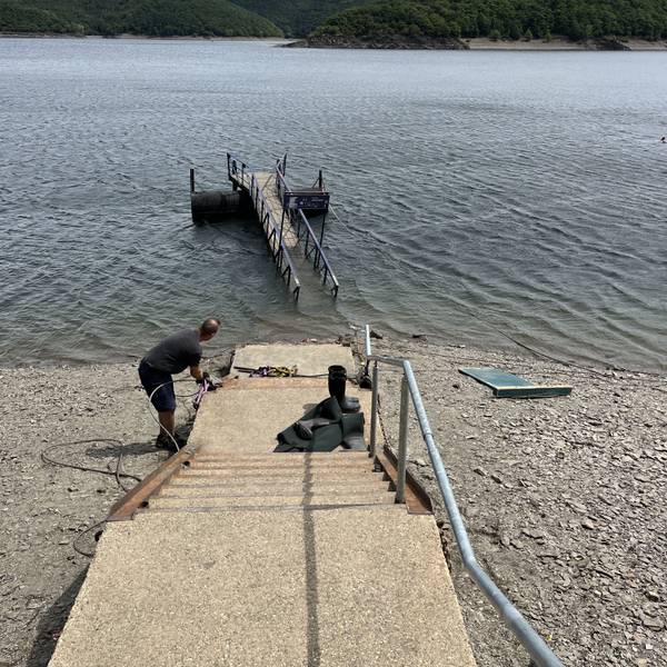 Blick auf den Rursee, wo eine Anlegebrücke im Wasser treibt.
