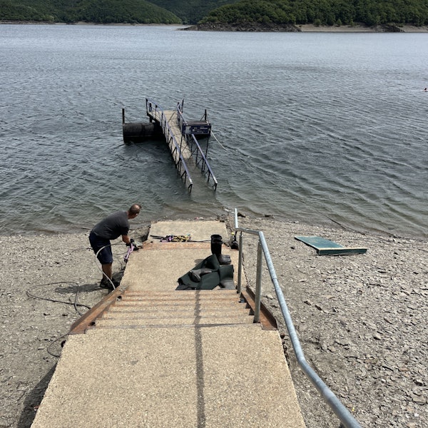 Blick auf den Rursee, wo eine Anlegebrücke im Wasser treibt.