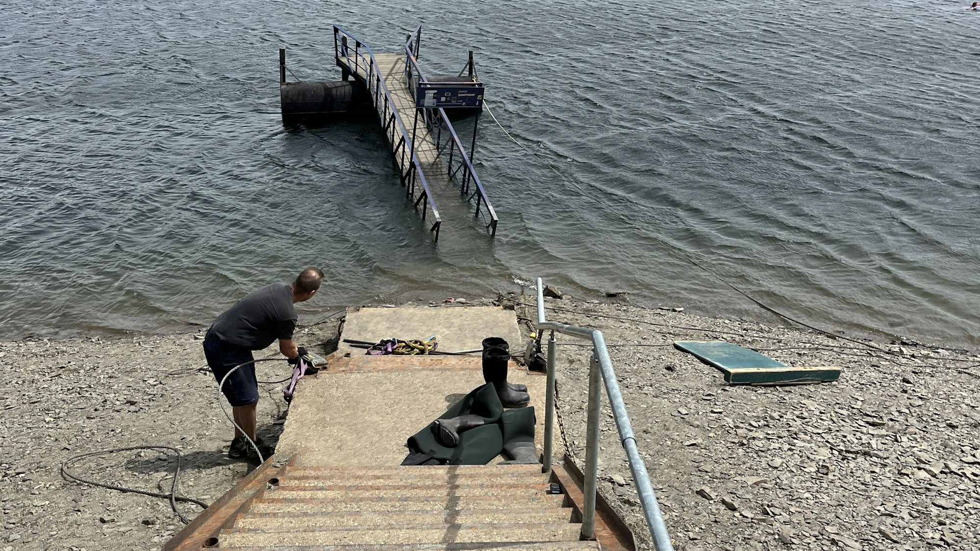 Blick auf den Rursee, wo eine Anlegebrücke im Wasser treibt.