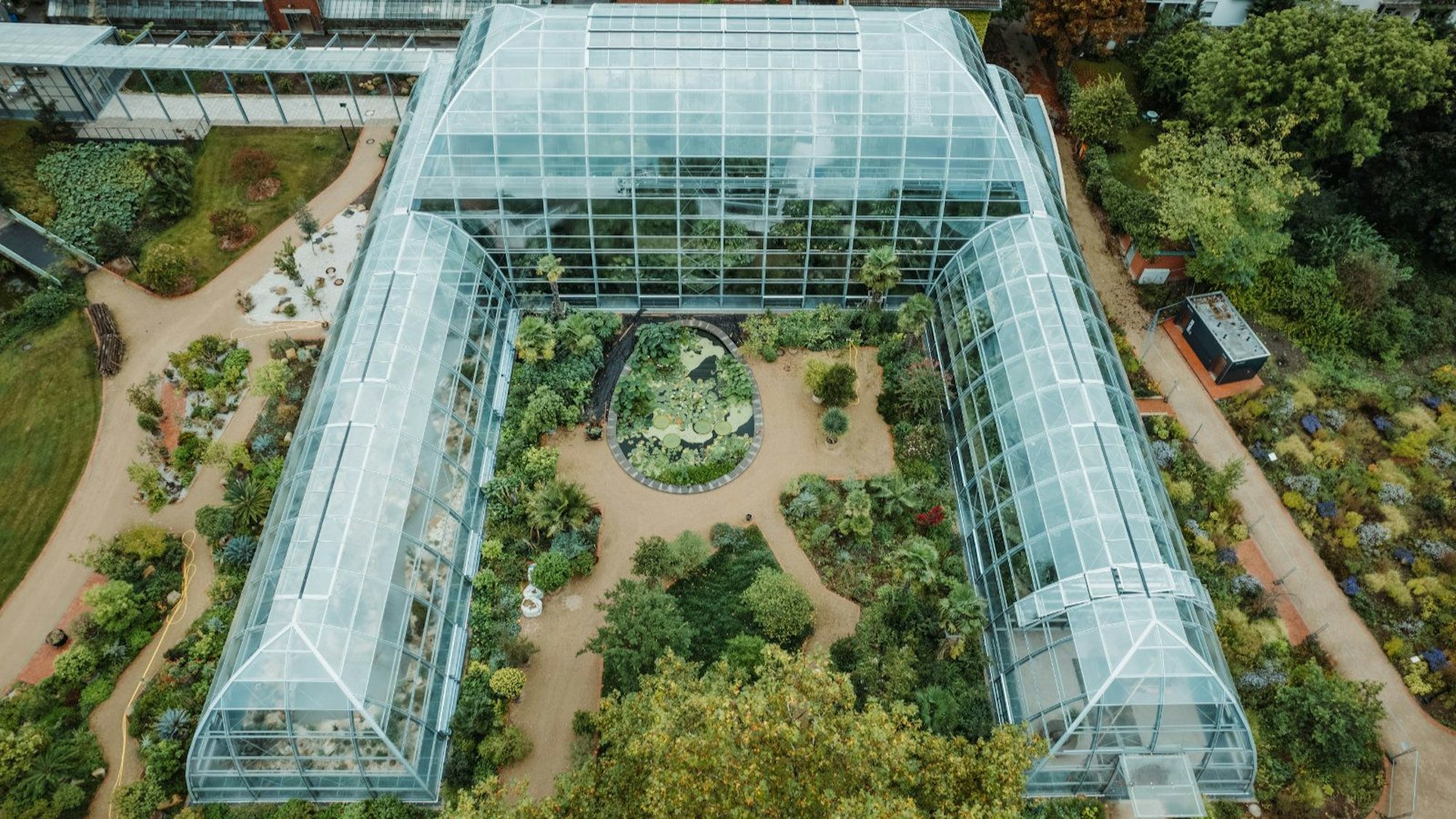 Luftaufnahme der U-förmigen Schaugewächshäuser mit Bepflanzung im Außenbereich