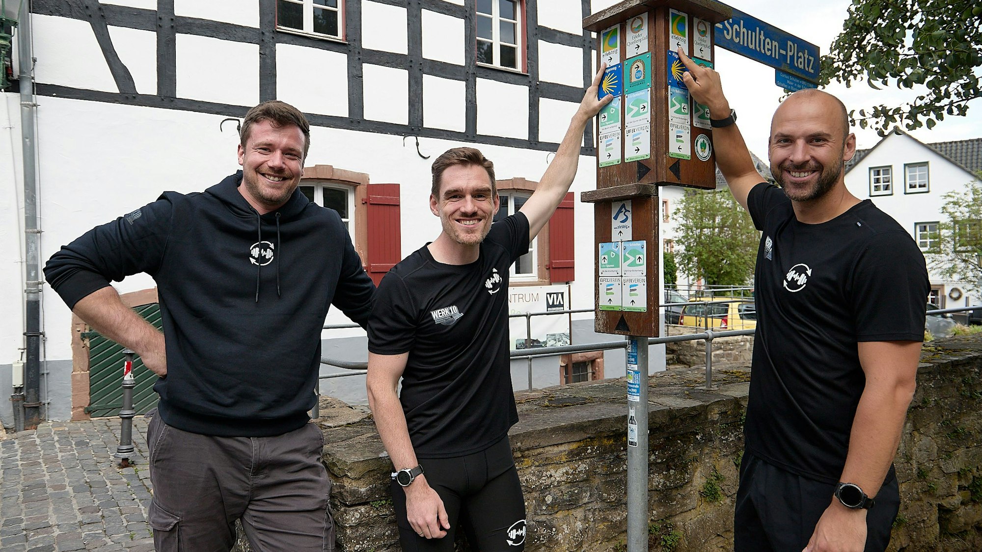 Den Eifelsteig fest im Blick haben Henrik Züll (von links), Sebastian Nelles und Andreas Winkler (rechts), die neben einem Wanderwegweiser stehen.