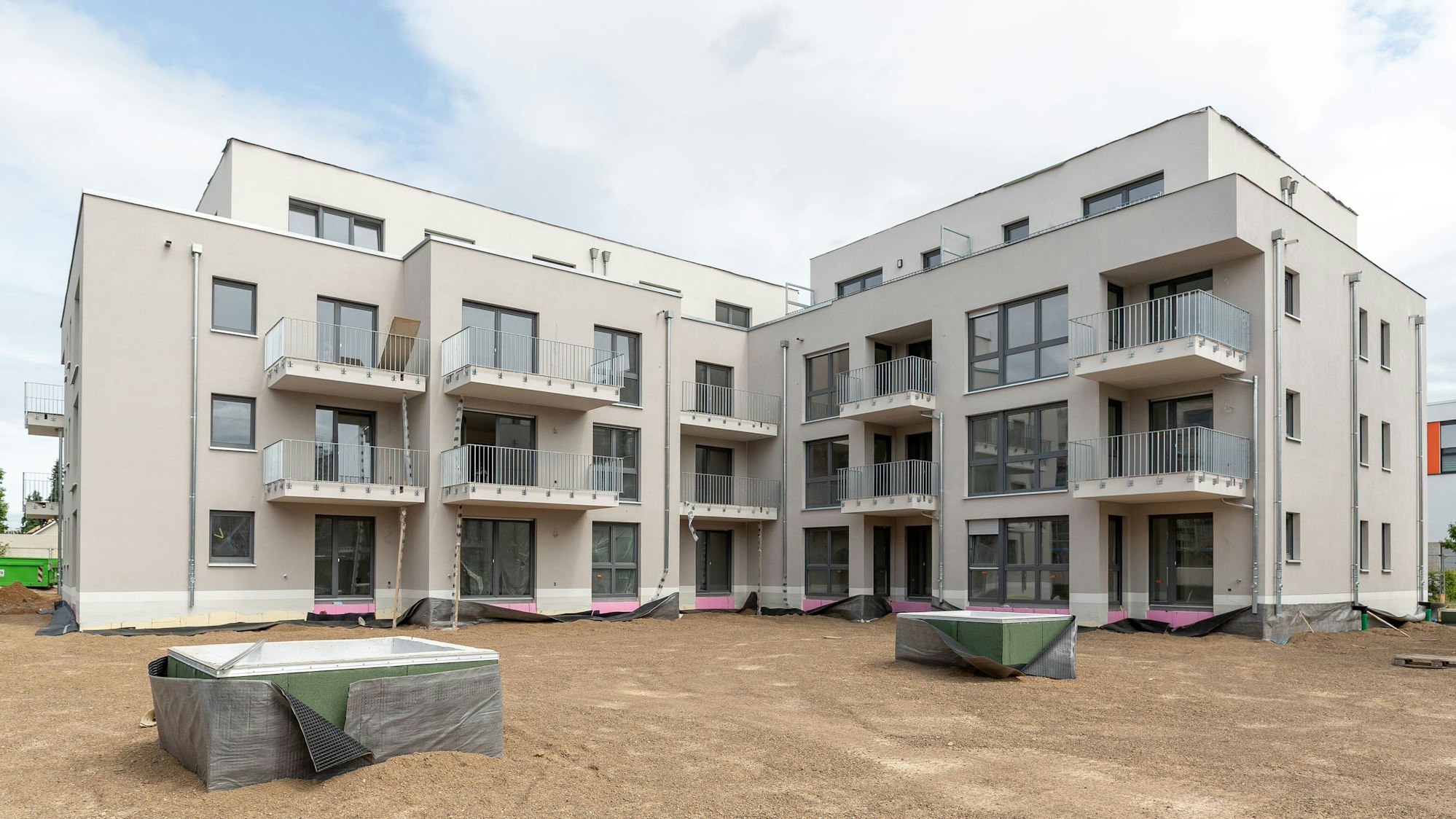 Das Bild zeigt eine der fertigen Wohnhäuser mit drei Geschossen und einem vierten Staffelgeschoss.