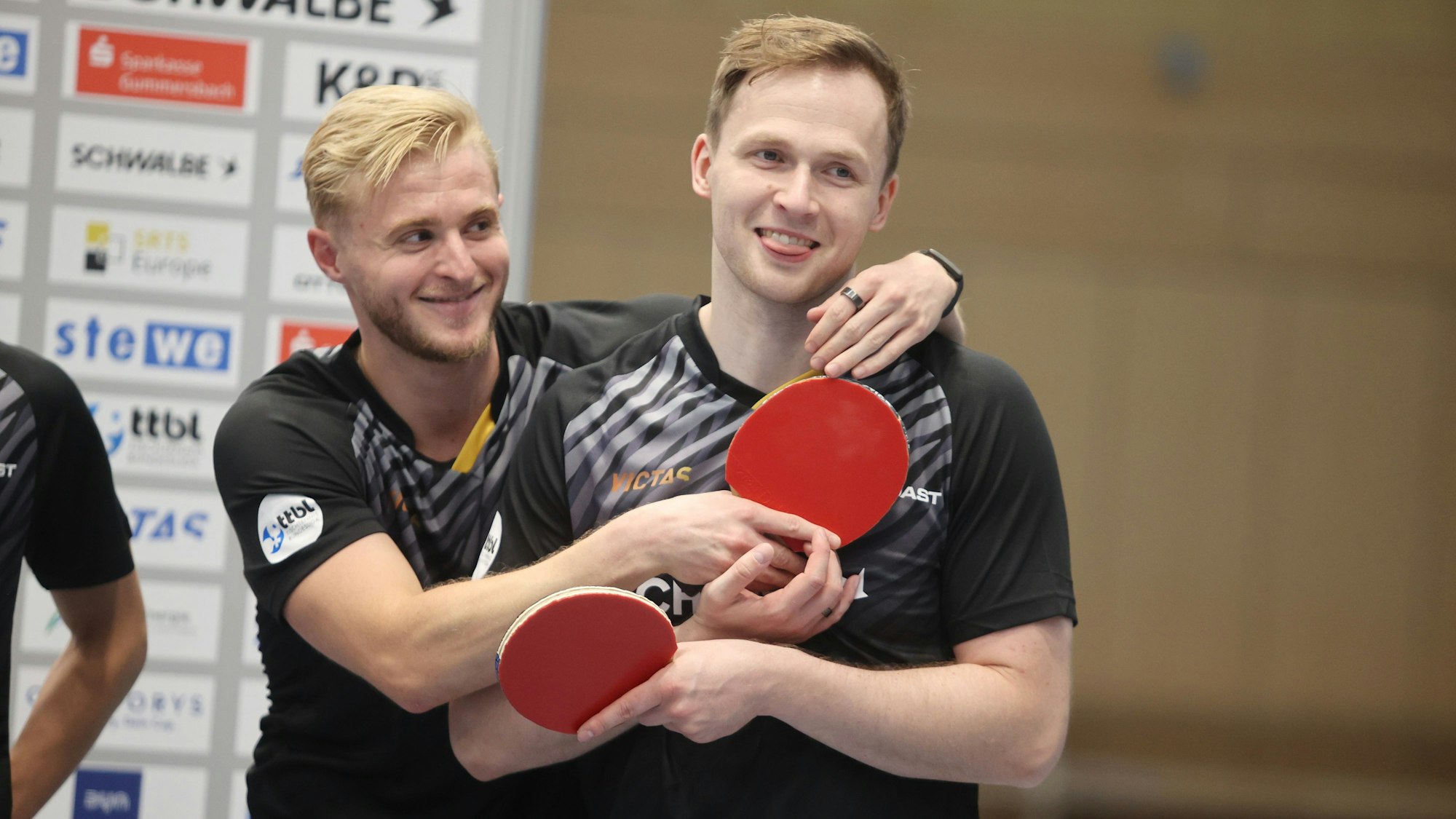 Die Tischtennisspieler Benedikt Duda und Romain Ruiz liegen sich lachend in den Armen.
