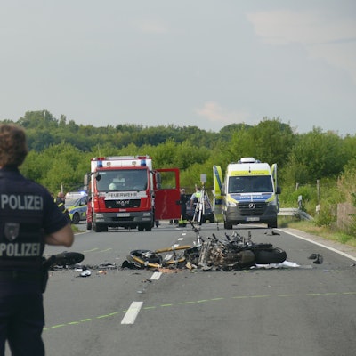 Polizisten blicken in Richtung der Unfallstelle auf der Alten Kölner Straße.