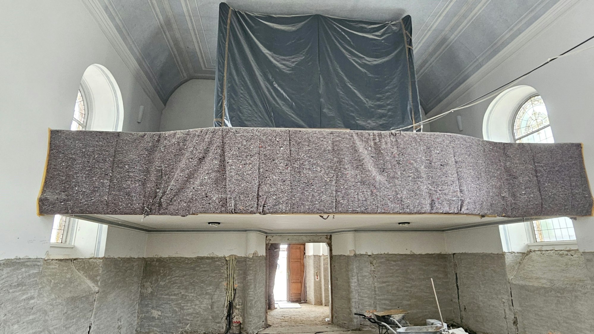 Zu sehen ist die mit einer schwarzen Folie eingehauste Orgel auf der Empore.