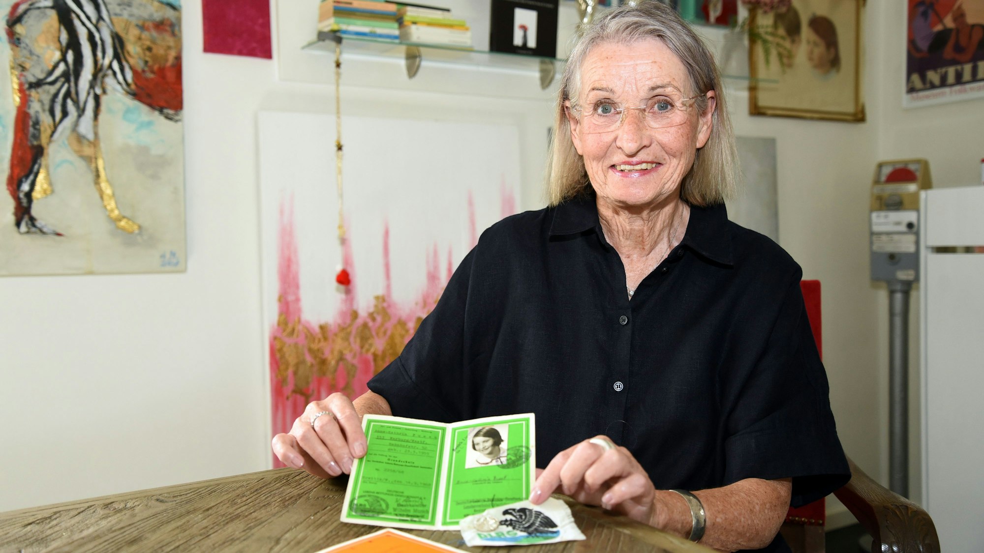 Anne-Kathrin Weiß sitzt an einem Tisch und zeigt ihr Schwimmabzeichen in die Kamera.