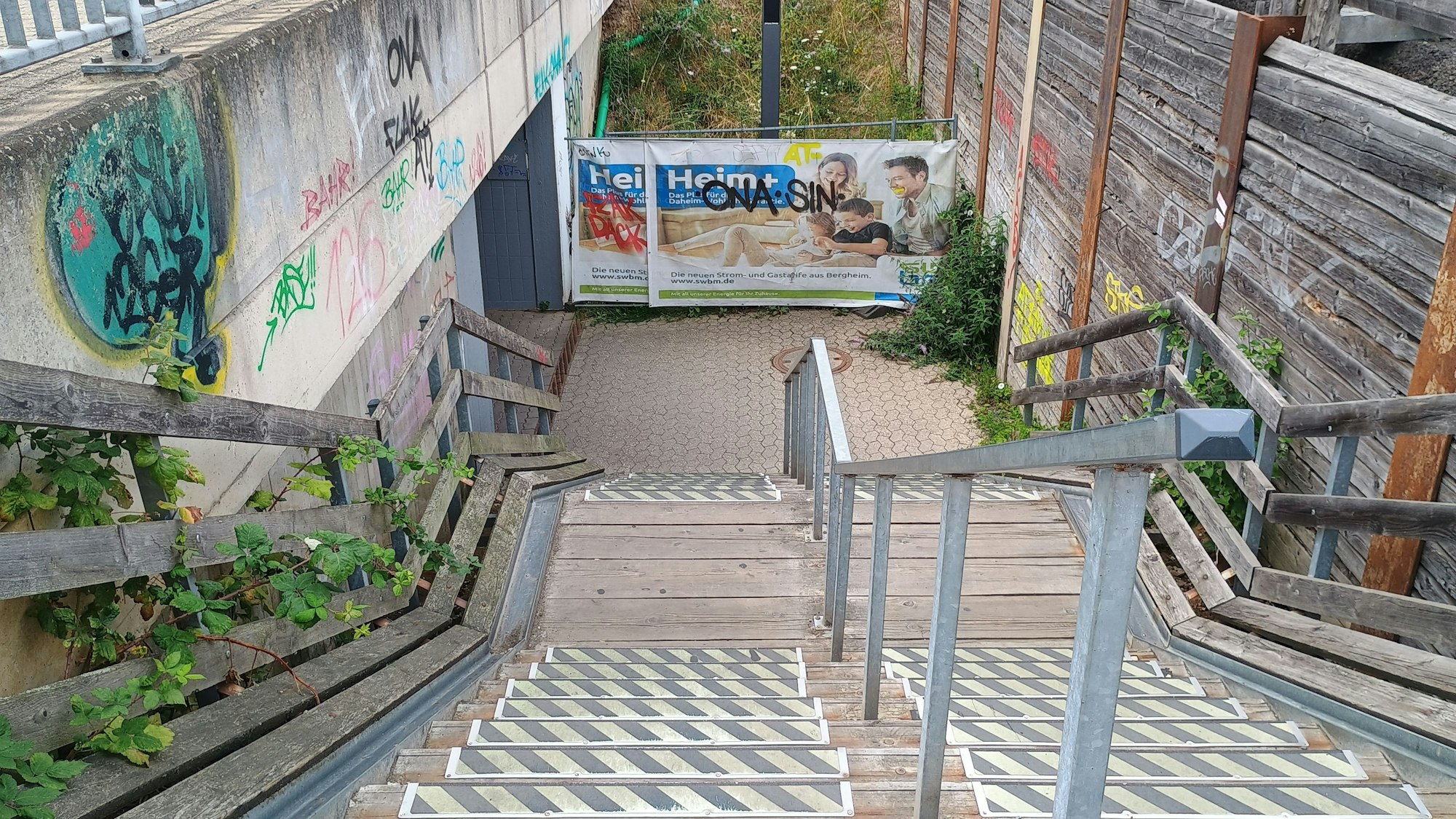 Zu sehen ist die Holztreppe, die zur Unterführung unter das Gleis führt.