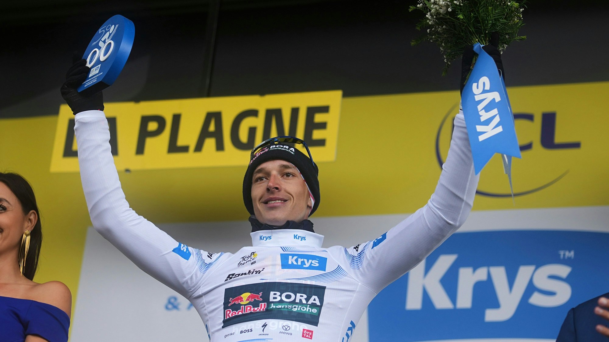 25.07.2025, Frankreich, La Plagne: Radsport: UCI WorldTour - Tour de France, Albertville - La Plagne (95,00 km), 19. Etappe. Der Deutsche Florian Lipowitz vom Team Red Bull - Bora - Hansgrohe, der das Weiße Trikot des besten Nachwuchsfahrers trägt, jubelt auf dem Podium. (NEU - alternativer Bildausschnitt) Foto: Thibault Camus/AP/dpa +++ dpa-Bildfunk +++