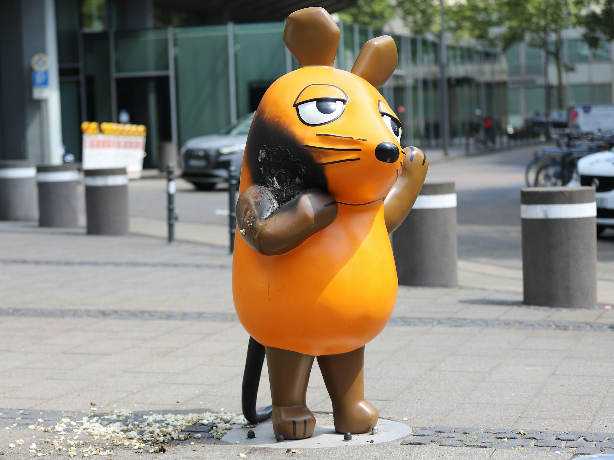 Mit einem großen Brandfleck steht die Maus vor dem WDR-Gebäude. Unbekannte hatten die Figur – ein beliebtes Fotomotiv in der Innenstadt – in der Nacht in Brand gesetzt.