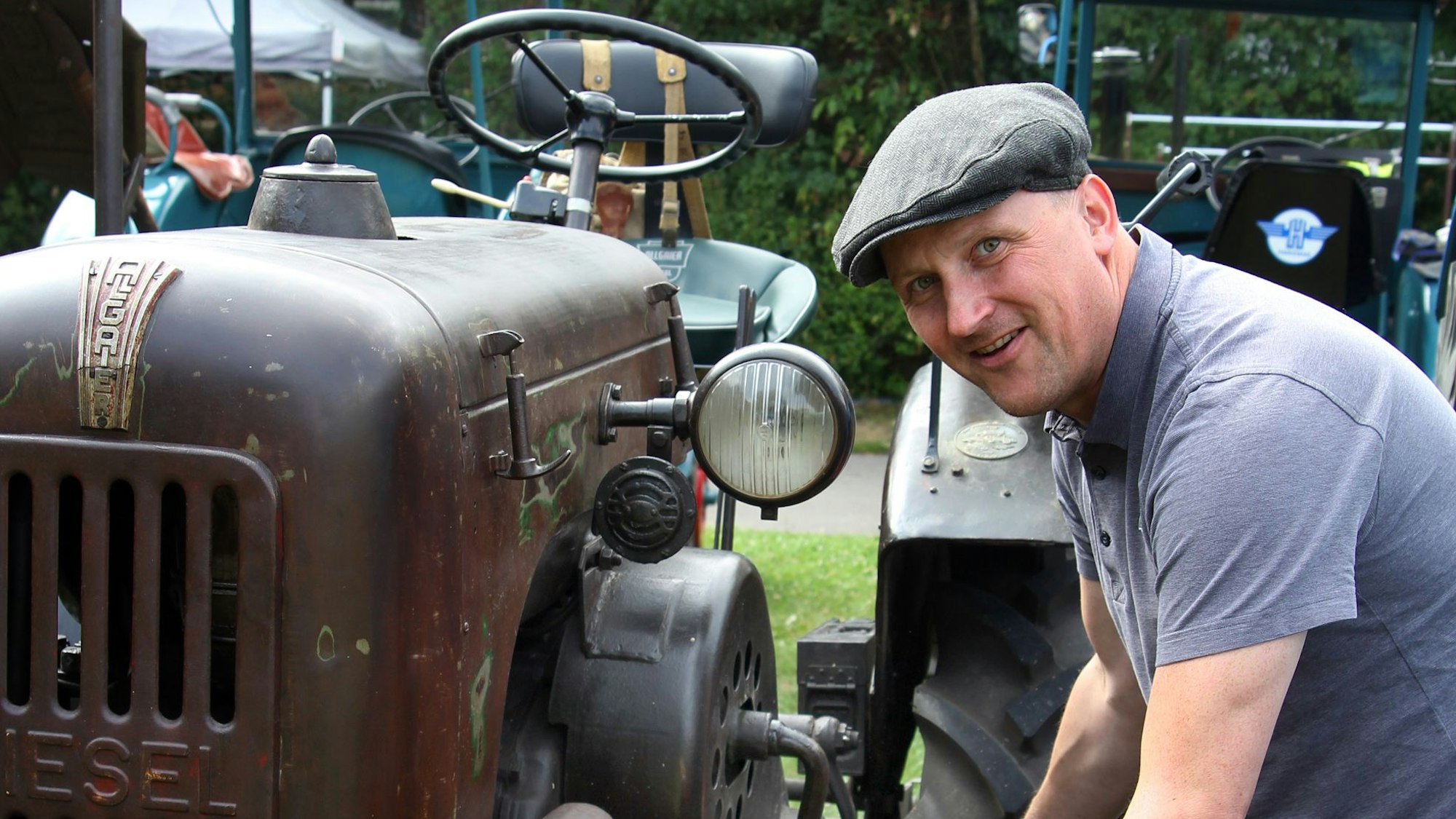 Das Foto zeigt einen Mann an einem alten Trecker.