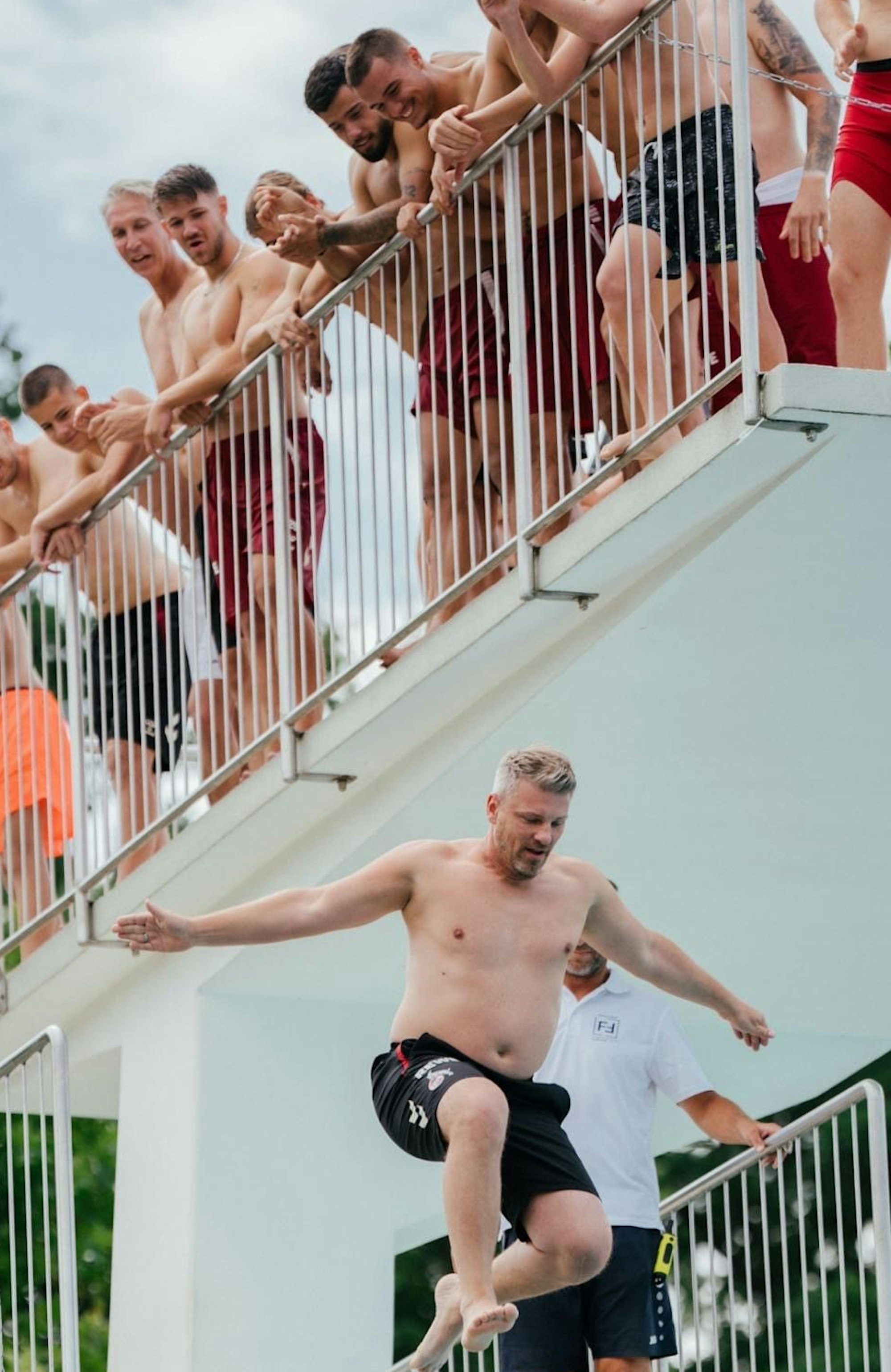 FC-Trainer Lukas Kwasniok wird im Freibad von Fürtsenfeld (Österreich) beim Sprung aus fünf Metern Höhe von seinem Team beobachtet.