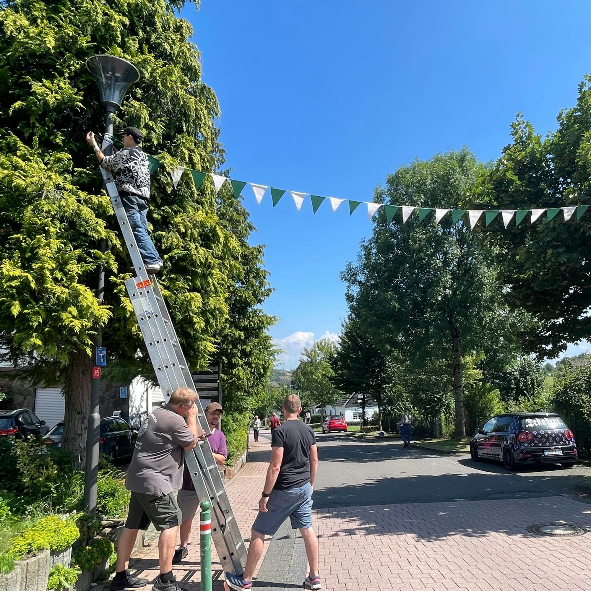 Hoch hinaus in Diensten des Müllenbacher Schützenfestes geht es für die Schmückgemeinschaft Graf-Albert-Straße: Die Wimpel wollen an den Masten angebracht werden.