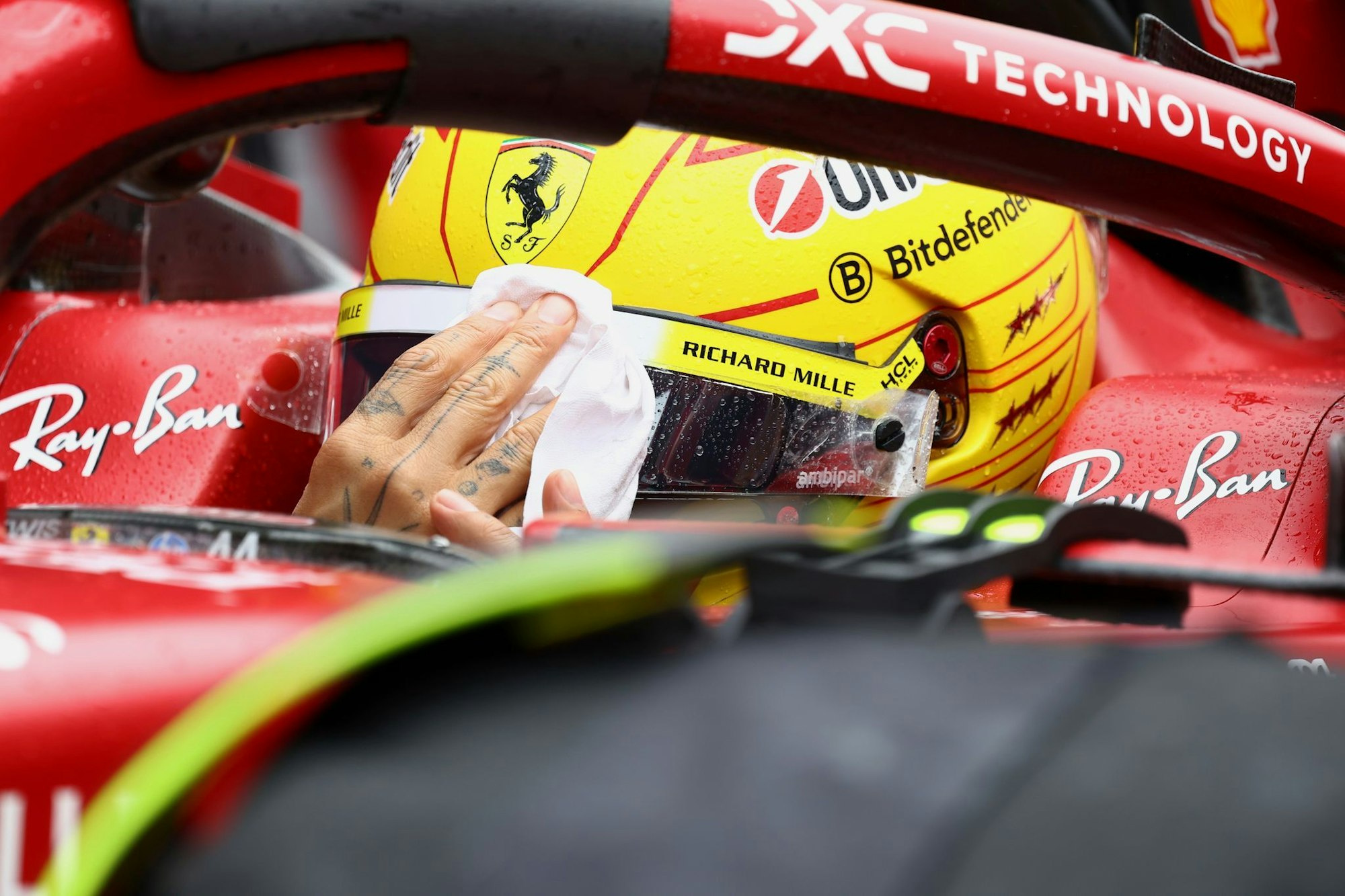 Lewis Hamilton wischt sich den Regen vom Visier.