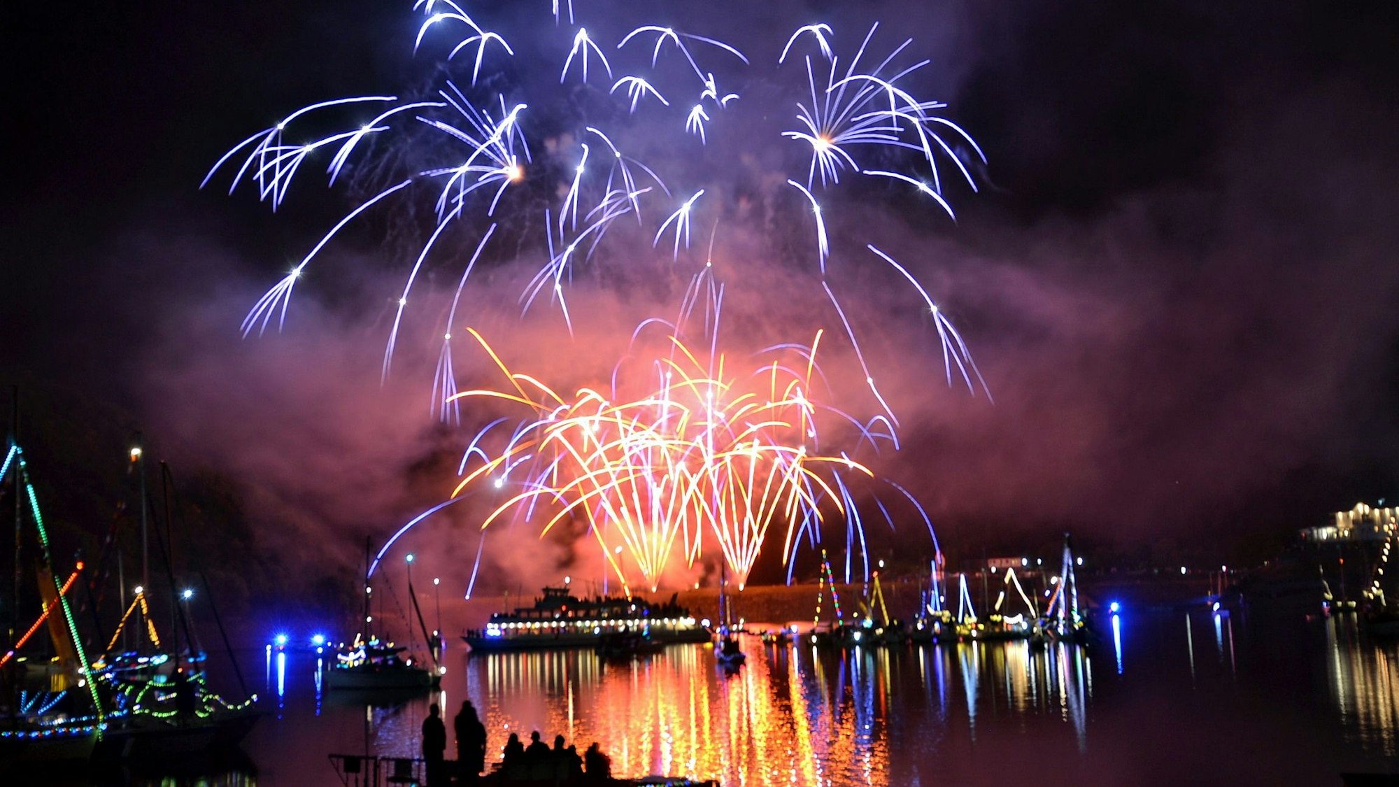 Am Nachthimmel über dem Rursee sieht man das imposante Höhenfeuerwerk, das sich in der Wasseroberfläche spiegelt.