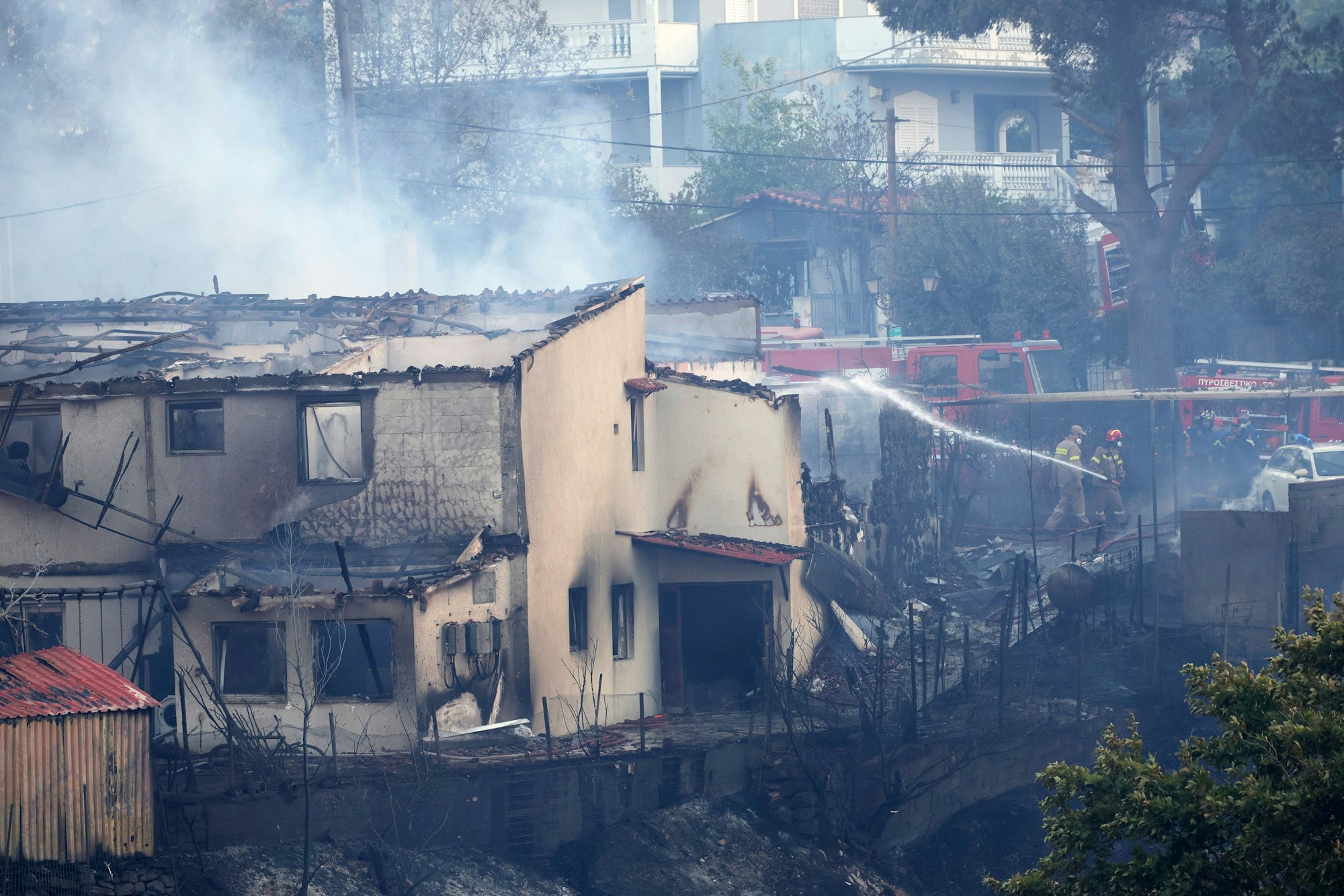 26.07.2025, Griechenland, Athen: Feuerwehrleute versuchen, ein Feuer in einem Haus während eines Waldbrandes im nordwestlichen Vorort Kryoneri zu löschen. Foto: Yorgos Karahalis/AP/dpa +++ dpa-Bildfunk +++