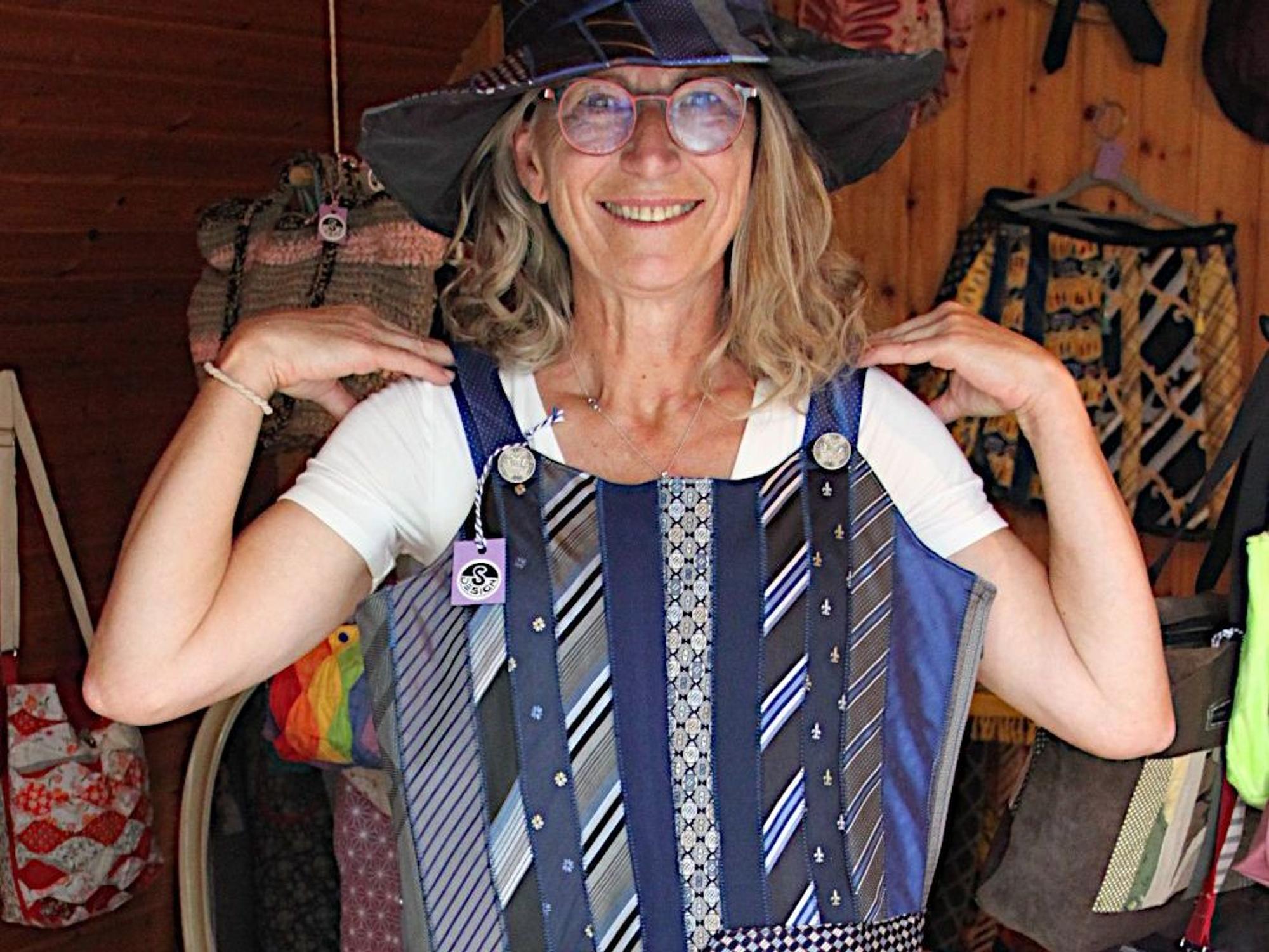 Eine Künstlerin präsentiert ein aus Krawatten genähtes Kleid und den dazu passenden Hut.