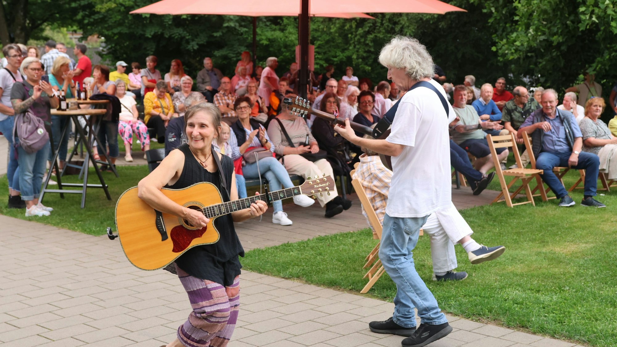 Eine Frau und ein Mann laufen Gitarre spielend durchs Publikum.