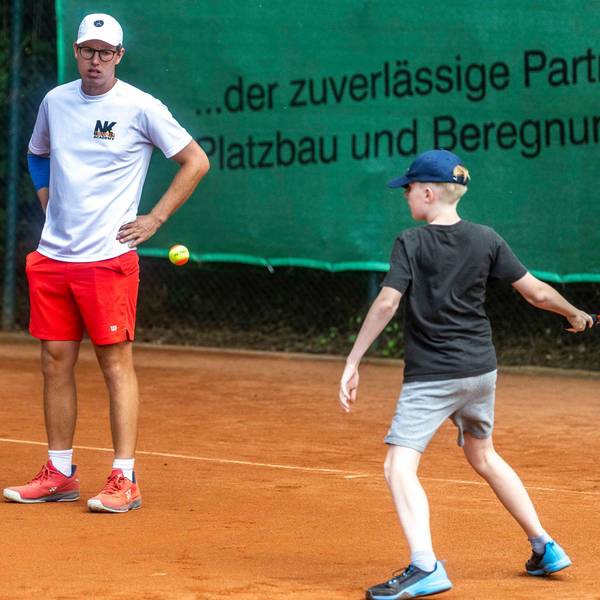 Tennistrainer Niklas Koch schaut einem Kind beim Tennisspielen zu.