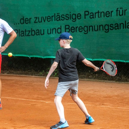 Tennistrainer Niklas Koch schaut einem Kind beim Tennisspielen zu.