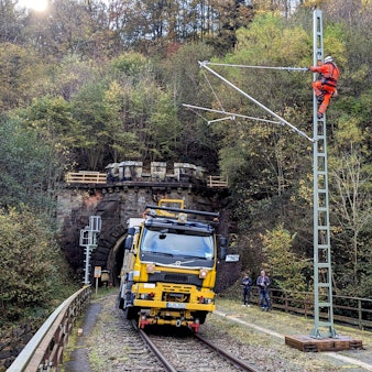 Arbeiter bei der Montage eines Flachmasts mit angelenktem Ausleger am Eingang zum Wilsecker Tunnel bei Kyllburg.