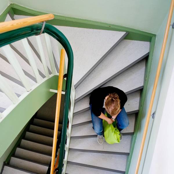 Eine junge Frau sitzt allein auf einer Treppe in Nienburg.