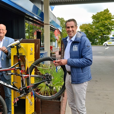 André Schiebahn (v.l.), Thomas Velling und Patrick Schmidder stehen neben der Servicestation, an der ein Fahrrad befestigt ist.