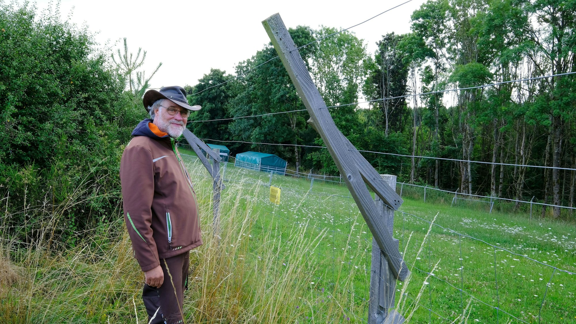 Ludger Coenen aus Nettersheim steht vor einem rund 2,20 Meter hohen Weidezaun, den er zum Schutz seiner Alpakas gebaut hat.