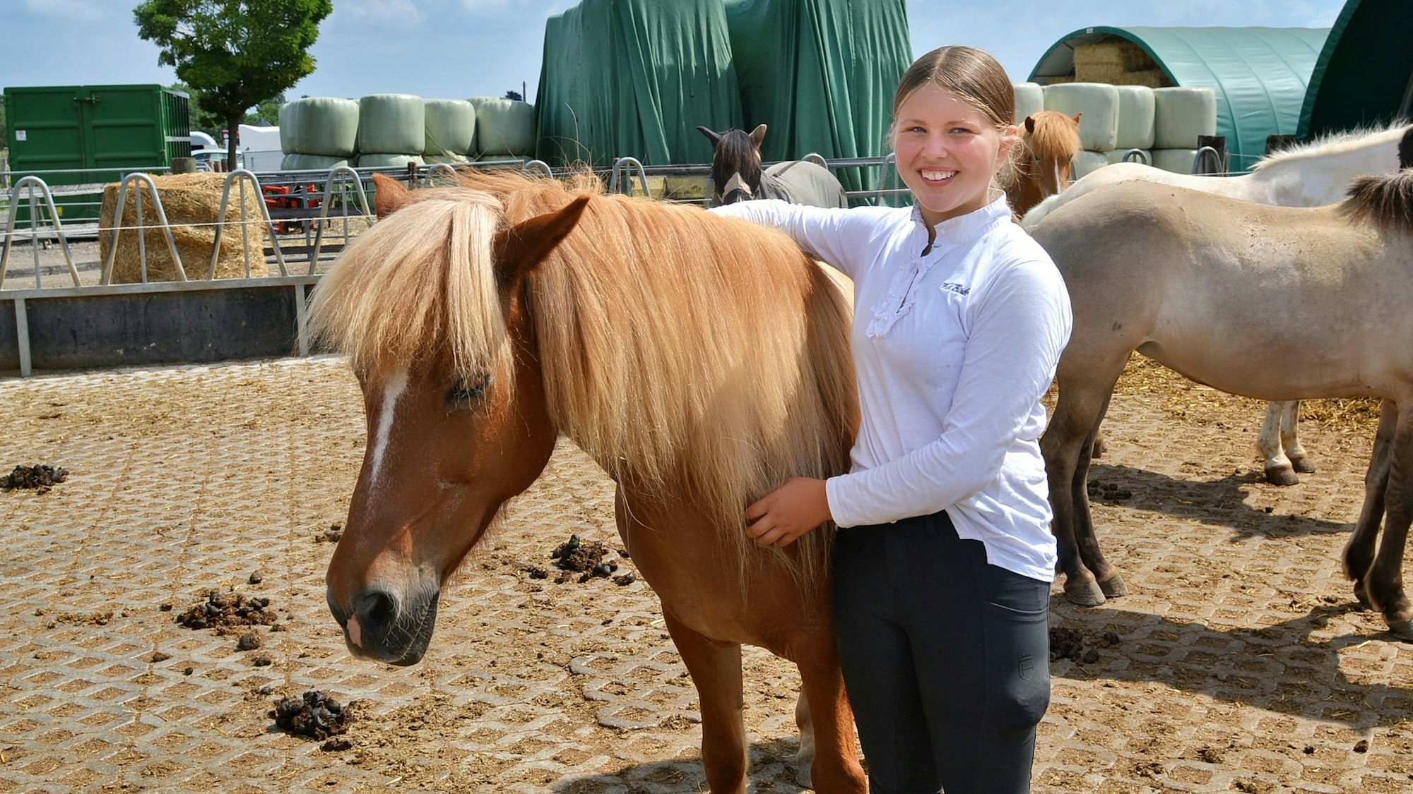 Leni Schönecker hat den Arm um ein Islandpferd gelegt und lächelt in die Kamera.