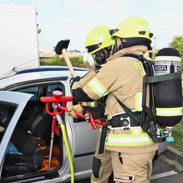 Feuerwehrleute löschen eine brennende Batterie in einem Elektrofahrzeug.