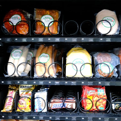 Die Detailaufnahme zeigt einen Teil des Warenangebots eines Verkaufsautomaten: Fleischprodukte wie Würstchen und Aufschnitt sowie verschiedene Süßigkeiten.