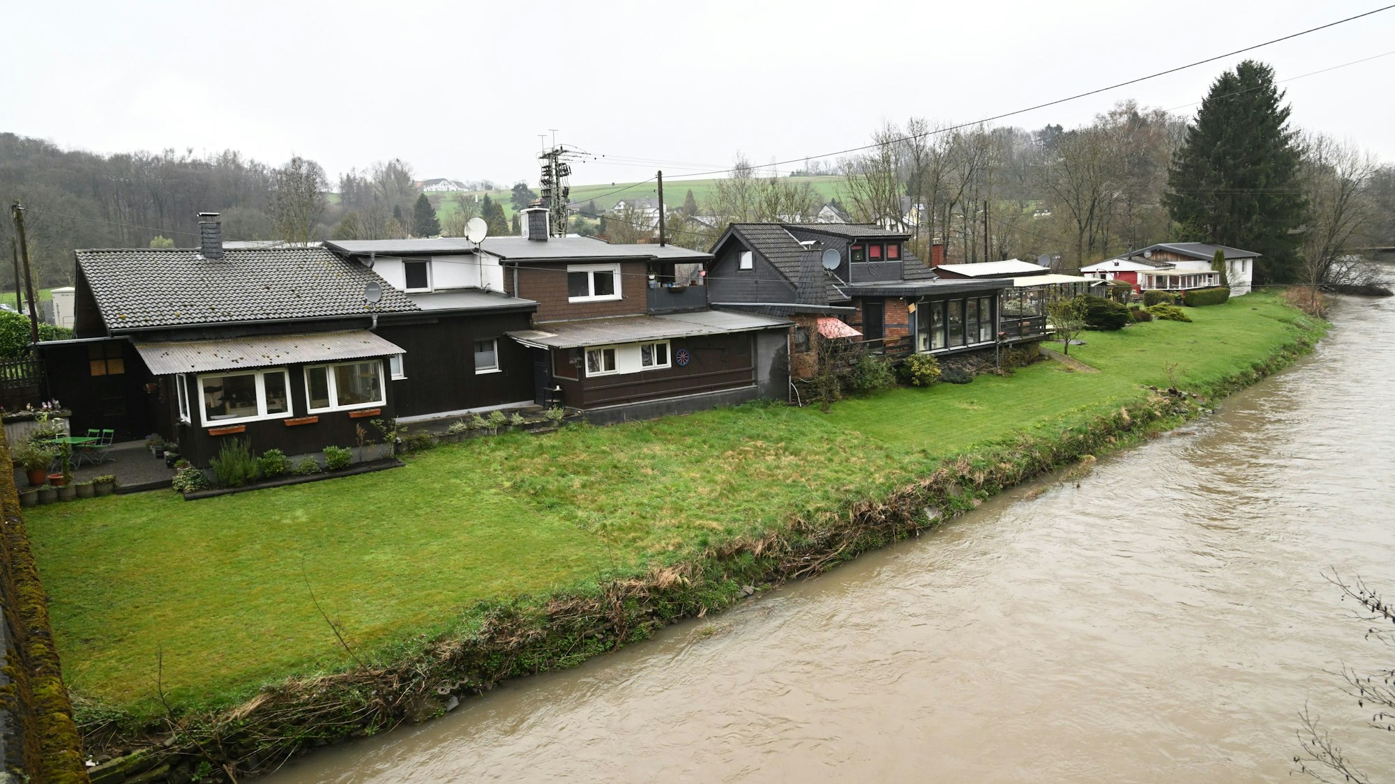 Am Aggerufer stehen mehrere Häuser.