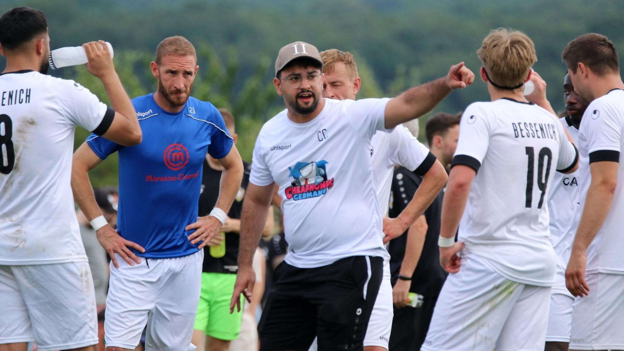 Der Trainer des SV Bessenich, Can Celik, spricht mit seinen Spielern und zeigt mit dem Finger die Richtung an.