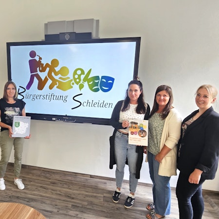 Marcel Wolter, Kerstin Wielspütz, Carmen Ammon, Petra Hilgers und Eva Urhahn stehen vor einem Großbildschirm mit dem Logo der Bürgerstiftung.