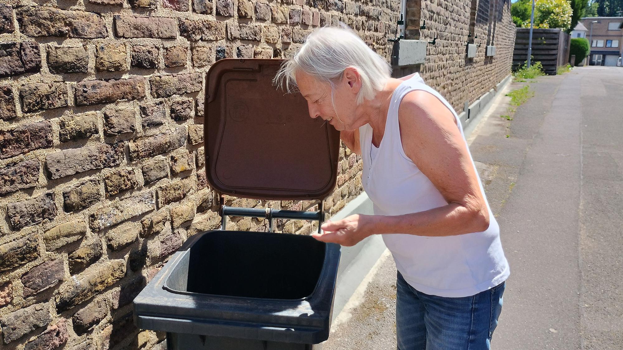 Das Bild zeigt, wie die Seniorin ihre Tonne öffnet und hineinschaut.