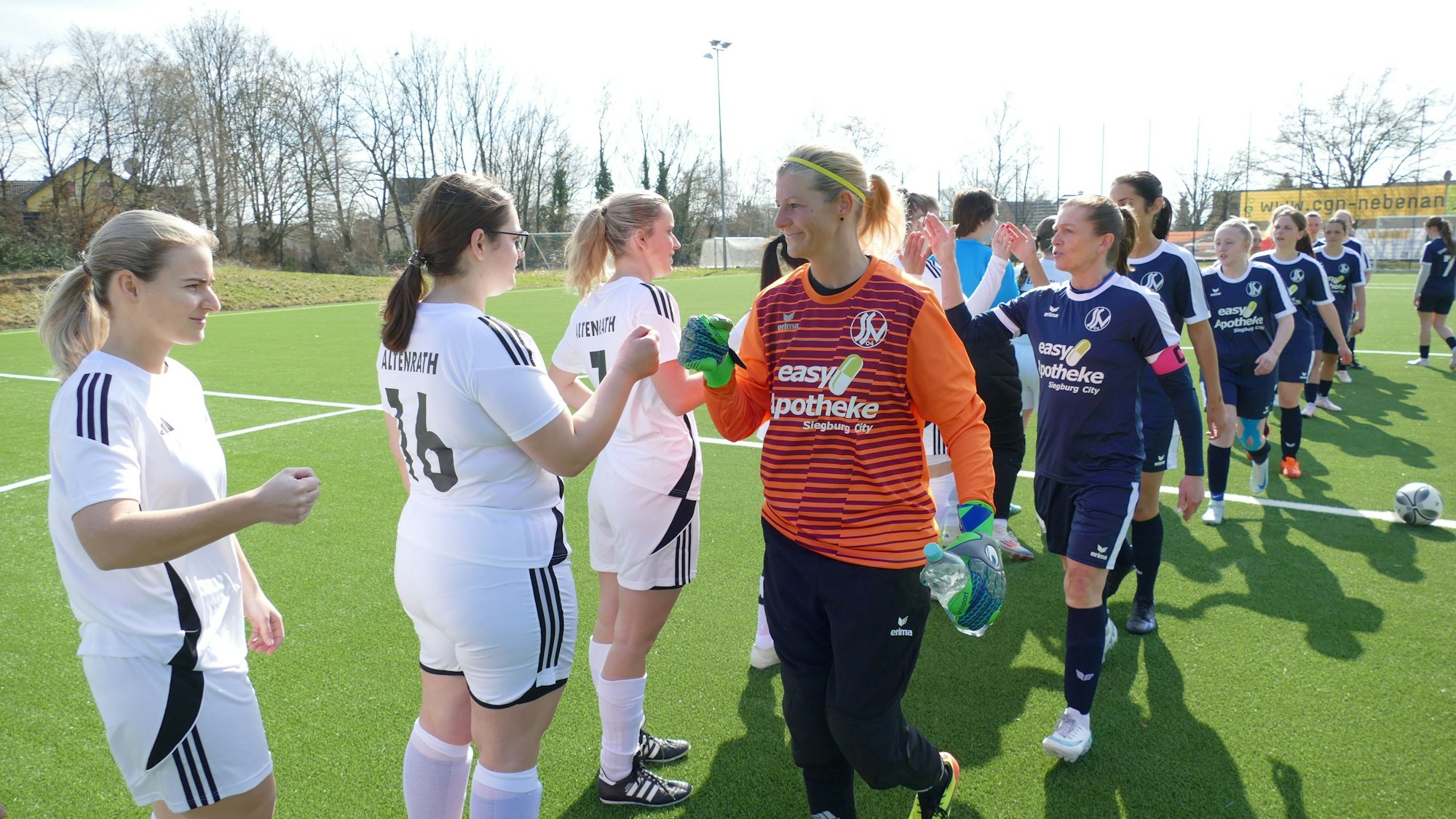 Zwei Frauen-Fußballteams klatschen sich ab.