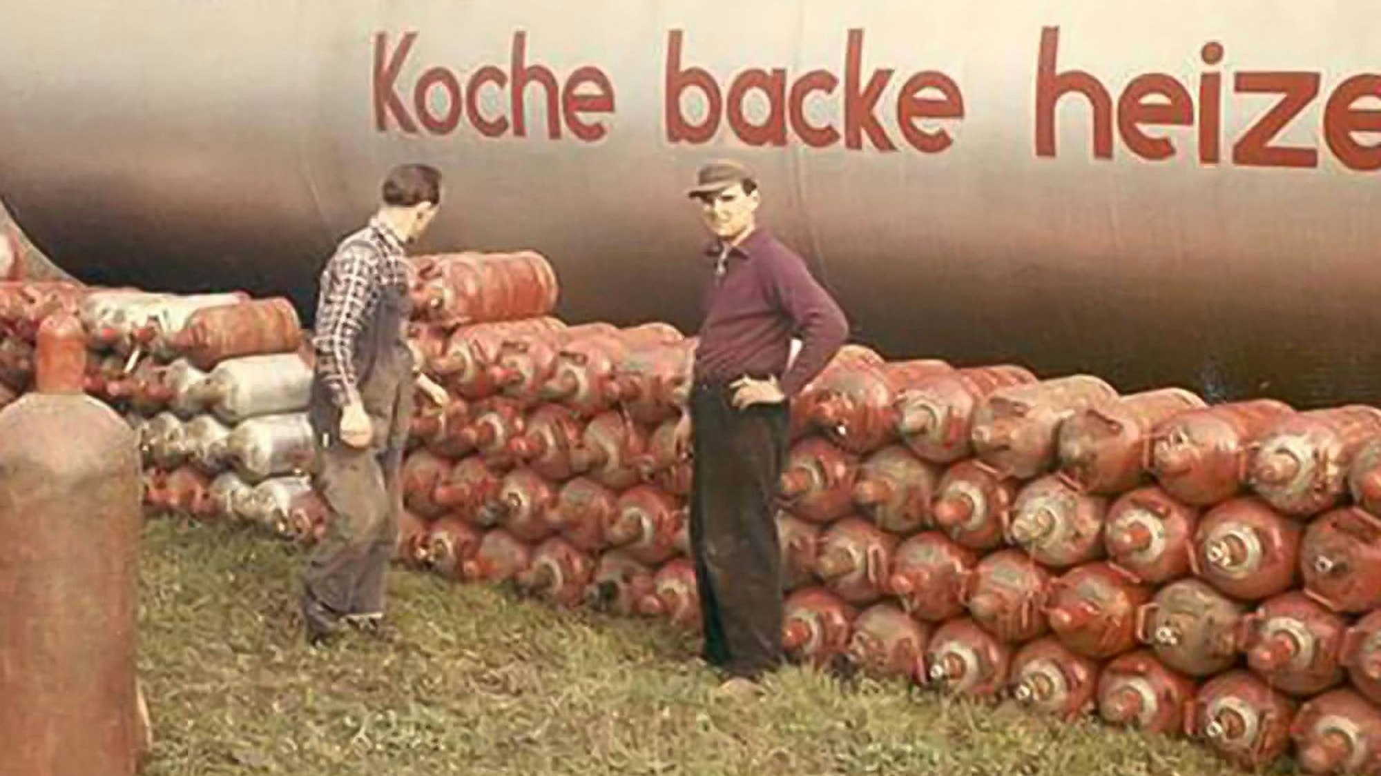 Zu sehen sind zwei Arbeiter, die vor vielen Gasflaschen stehen.