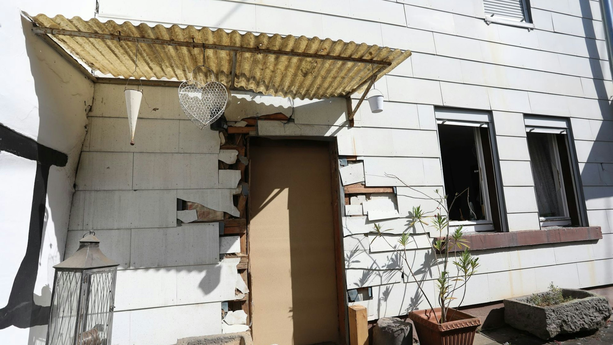 Eine Haustür ist provisorisch durch eine Holzplatte ersetzt worden.