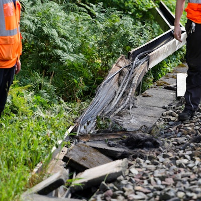 Mitarbeiter der Deutschen Bahn arbeiten an einem Gleisabschnitt in Düsseldorf. Dort wurde neben der Bahnstrecke Feuer in einem Kabeltunnel gelegt, der sechs Kabel in Mitleidenschaft zog. Foto: Christoph Reichwein/dpa